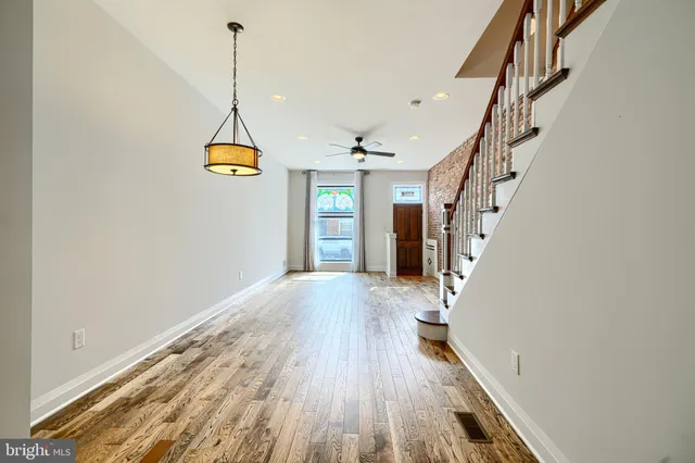 a view of empty room with wooden floor and fan