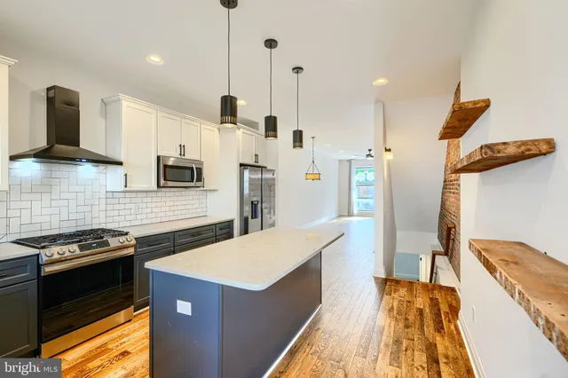 a kitchen with stainless steel appliances kitchen island a stove a sink and a refrigerator
