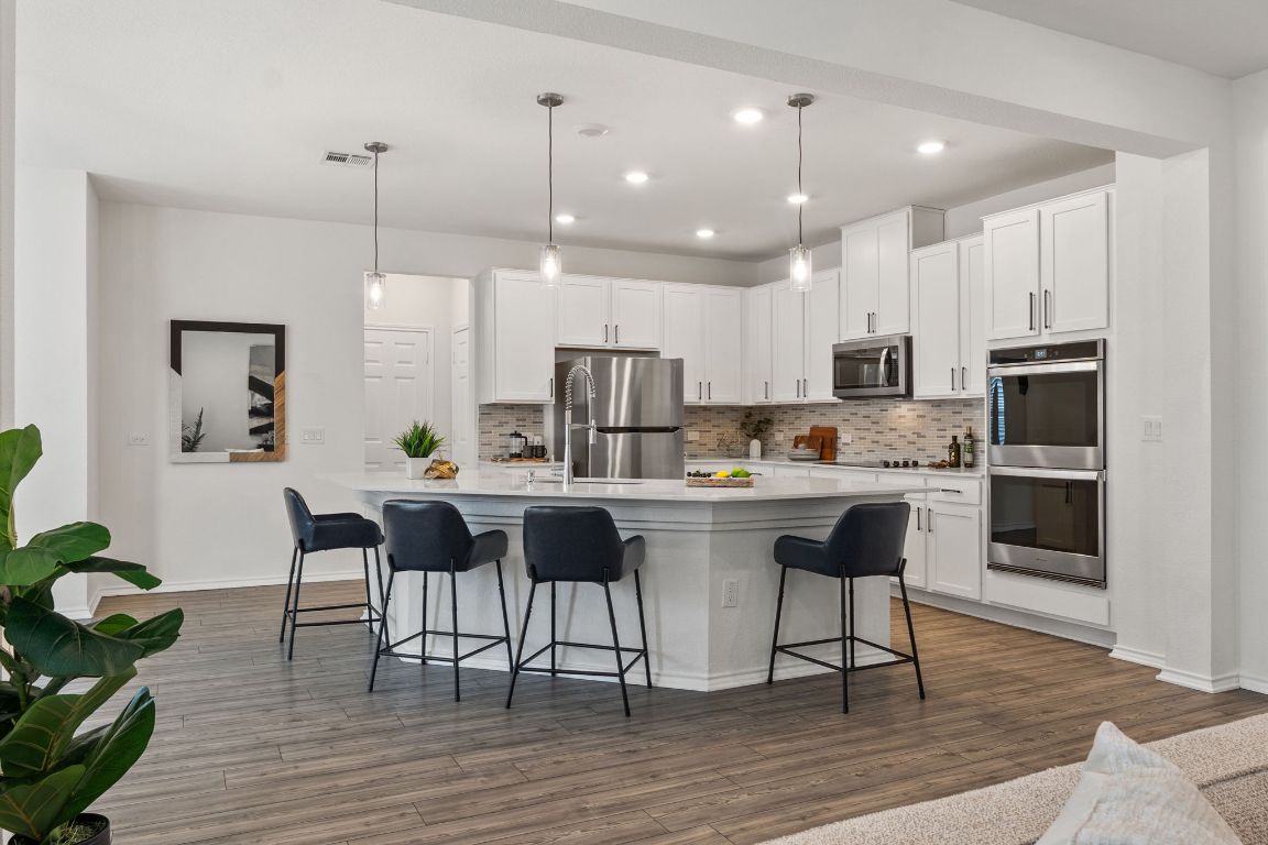 7808 Lawford Way Austin, TX 78744 - Photo 12 of 40 Kitchen with hanging light fixtures, a breakfast bar, recessed lighting, white cabinetry, and decorative backsplash