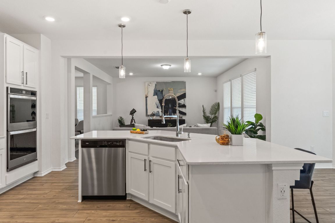 7808 Lawford Way Austin, TX 78744 - Photo 15 of 40 Kitchen featuring white cabinets, pendant lighting, light wood-style flooring, stainless steel appliances, and recessed lighting