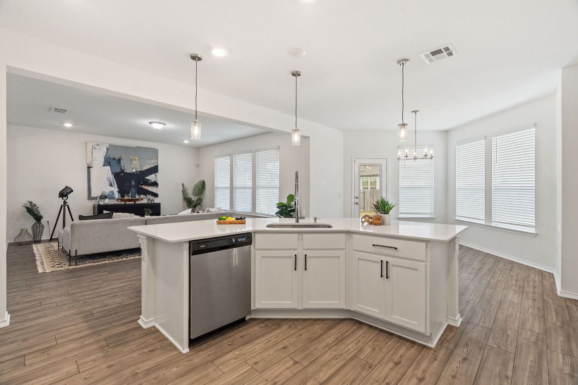 7808 Lawford Way Austin, TX 78744 - Photo 40 of 40 Kitchen with open floor plan, pendant lighting, dishwasher, white cabinets, and a kitchen island with sink