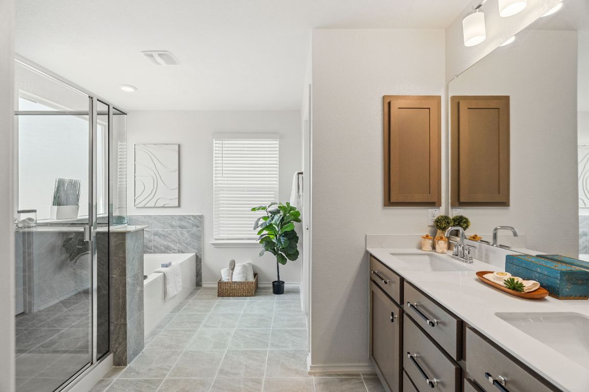 7808 Lawford Way Austin, TX 78744 - Photo 22 of 40 Full bathroom featuring a bath, double vanity, a shower stall, and light tile patterned floors