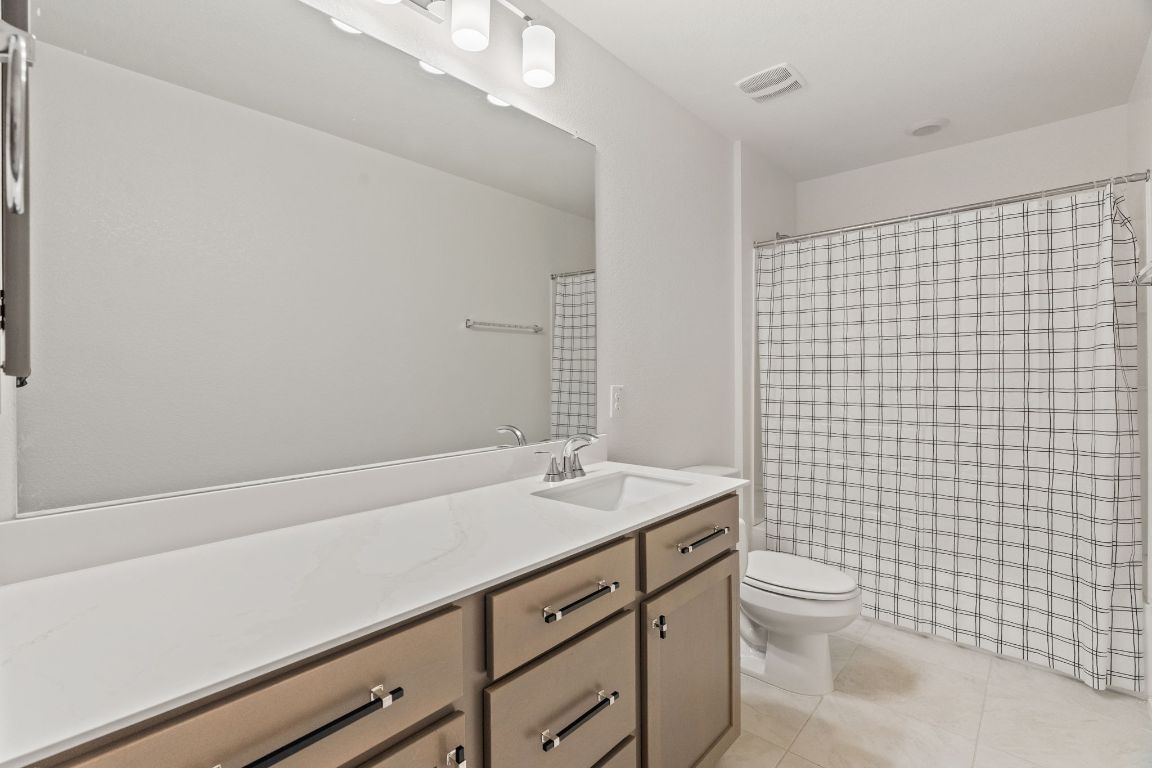 7808 Lawford Way Austin, TX 78744 - Photo 30 of 40 Full bathroom with vanity, light tile patterned floors, and a shower with curtain