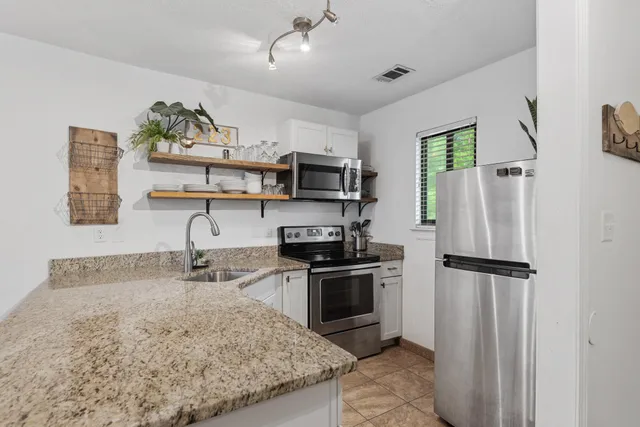 a kitchen with stainless steel appliances granite countertop a refrigerator a stove and a sink with wooden floor