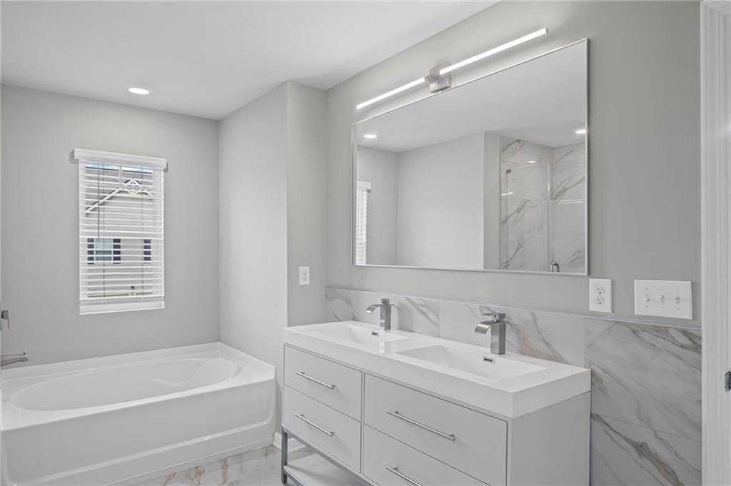 3650 River Rock Road Lithonia, GA 30038 - Photo 23 of 42 a bathroom with a bathtub a mirror a double vanity sink and