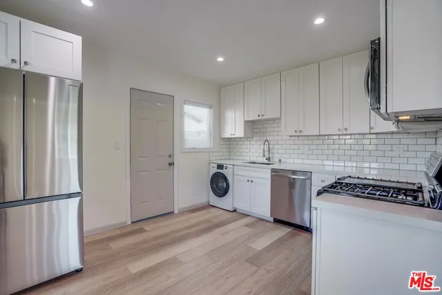 a kitchen with stainless steel appliances a refrigerator sink and white cabinets