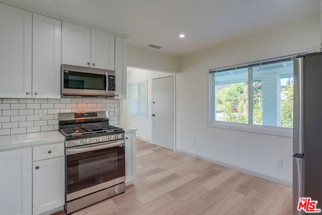 a kitchen with white cabinets and appliances