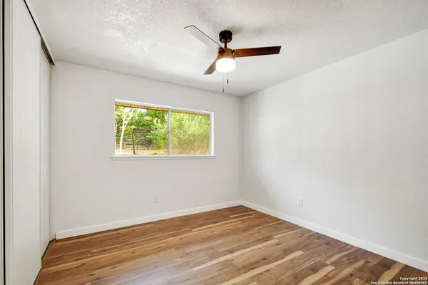 an empty room with wooden floor and windows
