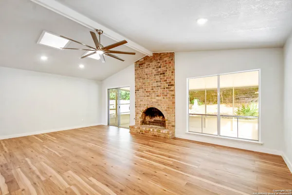 an empty room with windows and fireplace