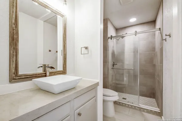 a bathroom with a granite countertop sink toilet and shower
