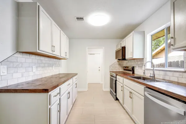 a kitchen with granite countertop a sink dishwasher stove and white cabinets with wooden floor