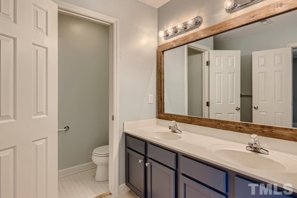5405 Staysail Court Raleigh, NC 27613 - Photo 14 of 28 a bathroom with a sink a toilet and a large mirror