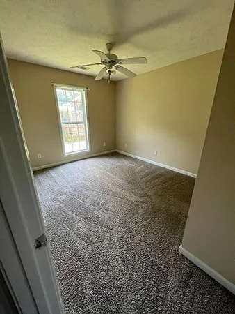 en empty room with windows and chandelier fan