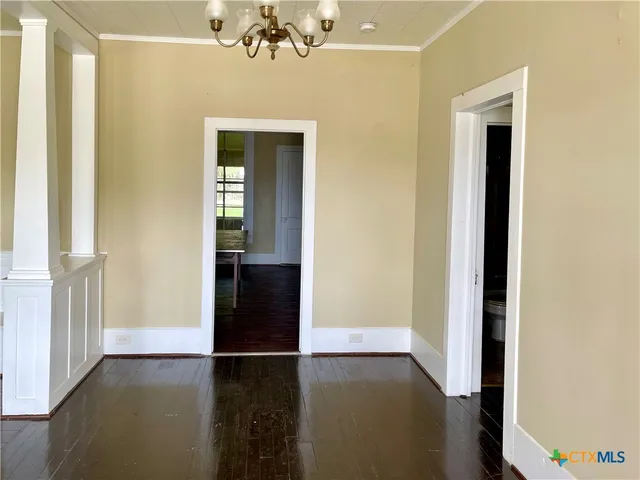 a view of a hallway with wooden floor and a livingroom
