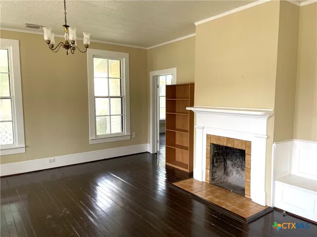 an empty room with wooden floor fireplace and windows