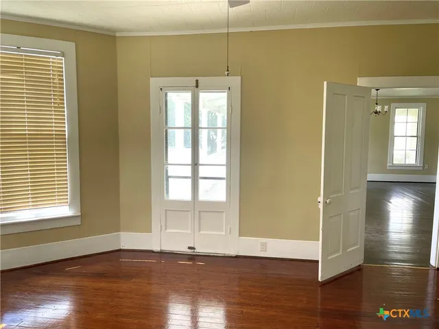 a view of an empty room with window and wooden floor