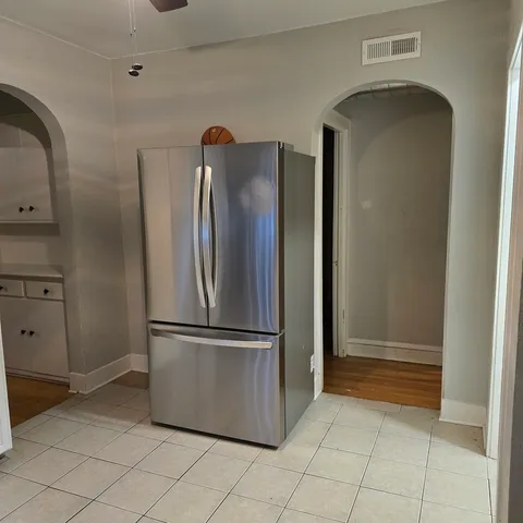 a view of a refrigerator in kitchen and white cabinets