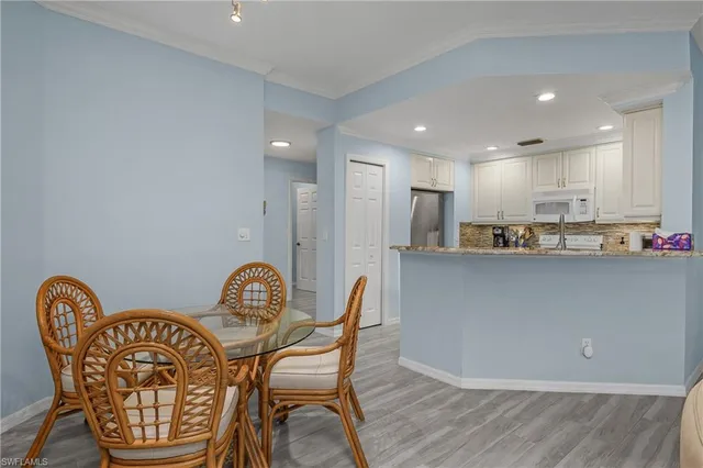 a kitchen with stainless steel appliances granite countertop a dining table chairs and a refrigerator