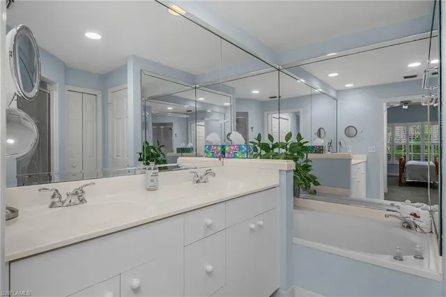 a bathroom with a tub a sink and a large mirror