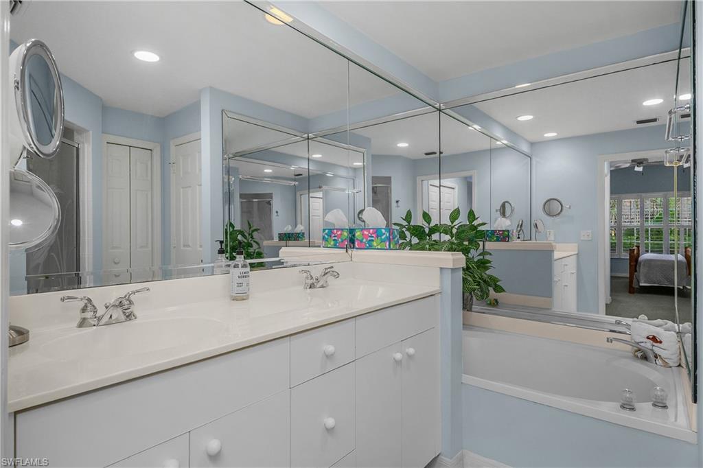 963 Egrets Run, Unit 102 Naples, FL 34108 - Photo 22 of 39 a bathroom with a tub a sink and a large mirror