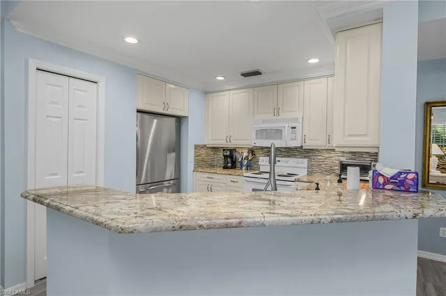 a kitchen with granite countertop kitchen island stainless steel appliances a sink refrigerator and cabinets