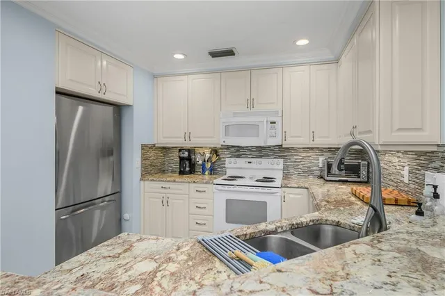 a kitchen with stainless steel appliances kitchen island granite countertop a refrigerator sink and cabinets