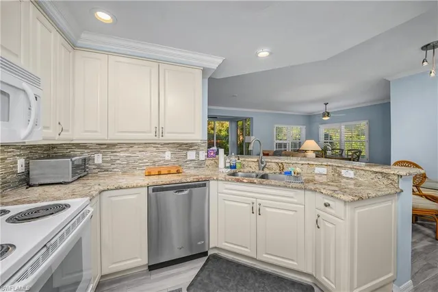 a kitchen with white cabinets sink and stove