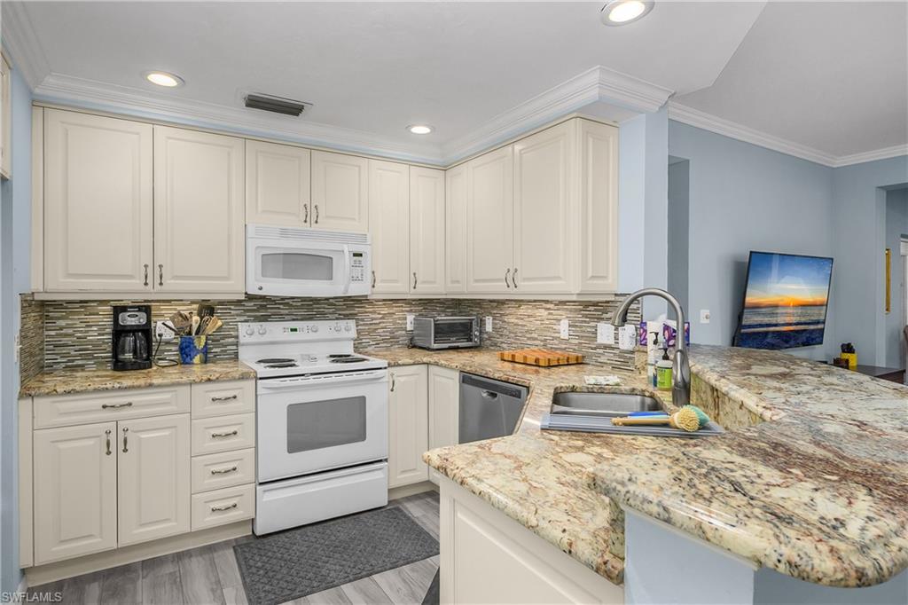 963 Egrets Run, Unit 102 Naples, FL 34108 - Photo 10 of 39 a kitchen with white cabinets and appliances