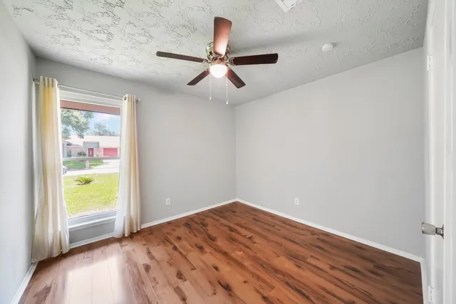 a view of empty room with wooden floor and fan