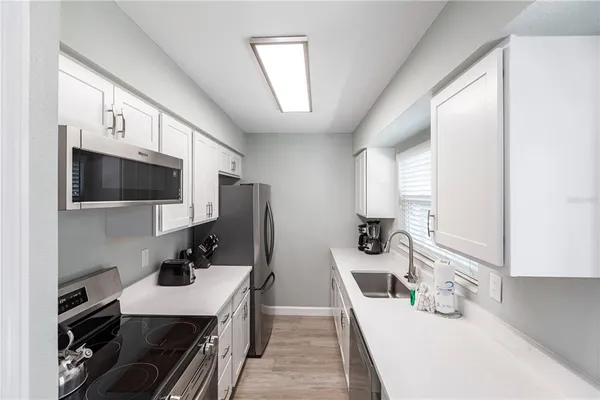 a kitchen with a sink stainless steel appliances a counter top space and cabinets