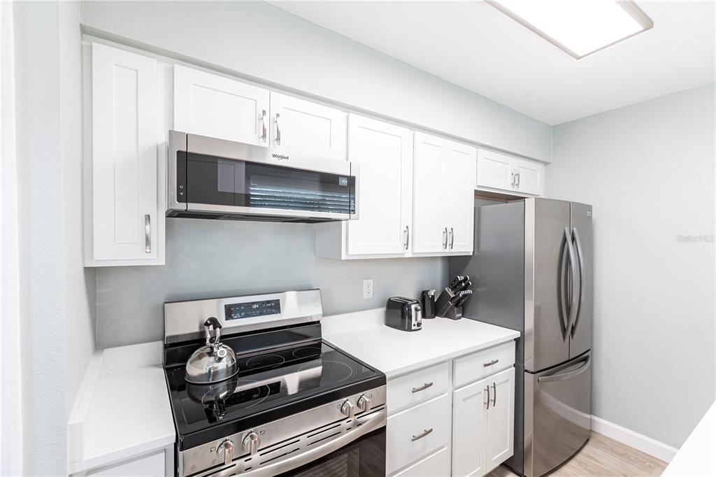 6020 Midnight Pass Road, Unit 10 Sarasota, FL 34242 - Photo 8 of 21 a kitchen with stainless steel appliances a stove a microwave and a refrigerator