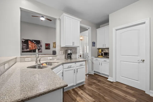 a kitchen with a sink dishwasher a stove and white cabinets with wooden floor