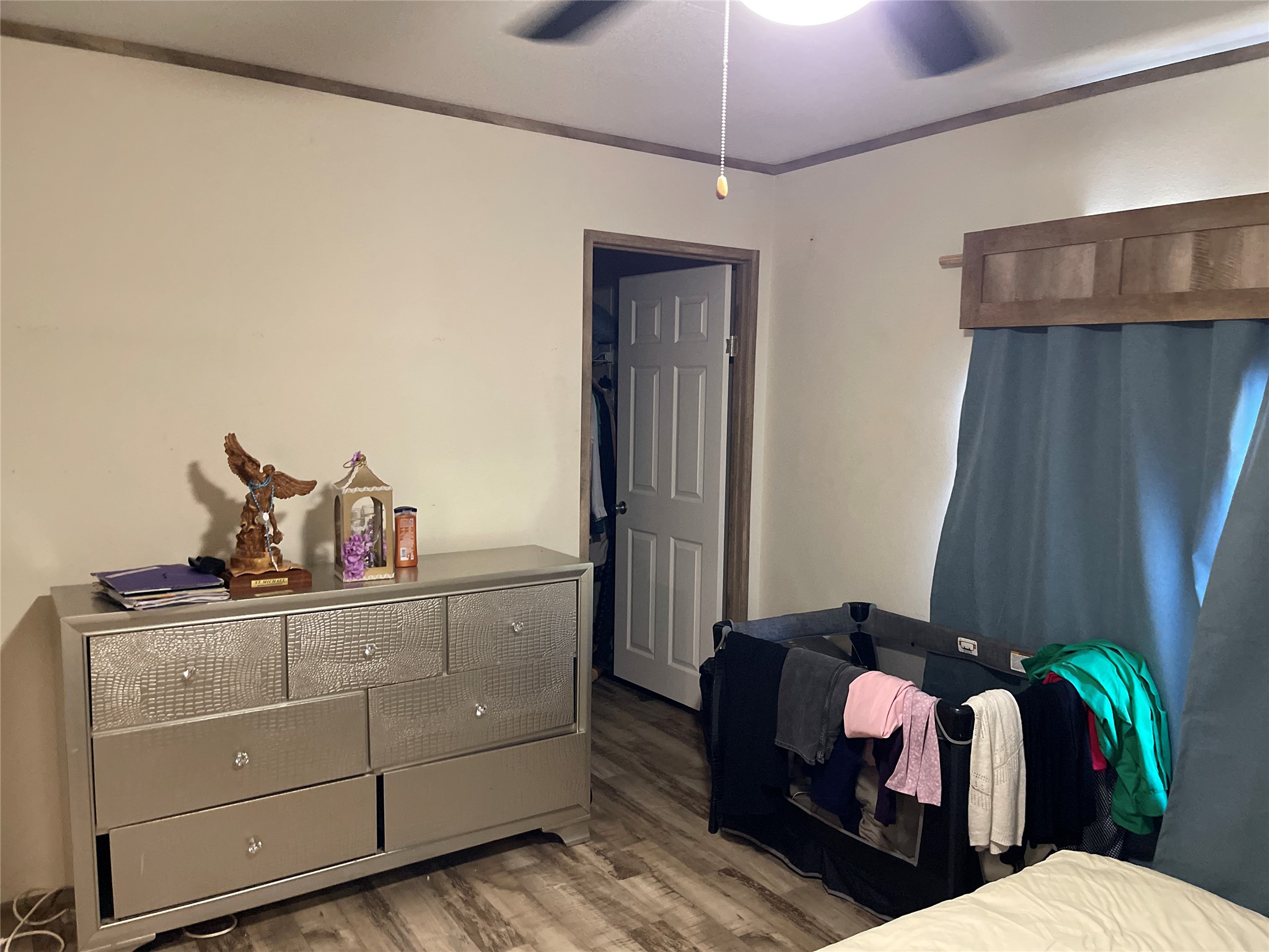 A quiet bedroom features durable wood-look flooring and an attached walk-in closet.