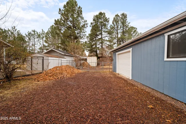 a backyard of a house with wooden fence and large trees