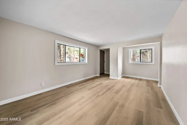 a view of an empty room with a window and wooden floor