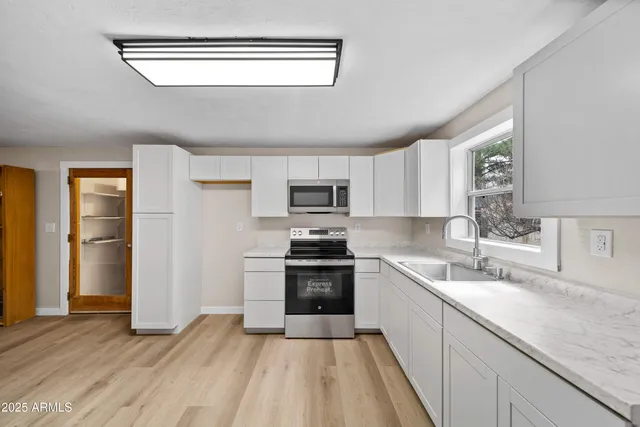a kitchen with granite countertop a sink wooden floor and stainless steel appliances