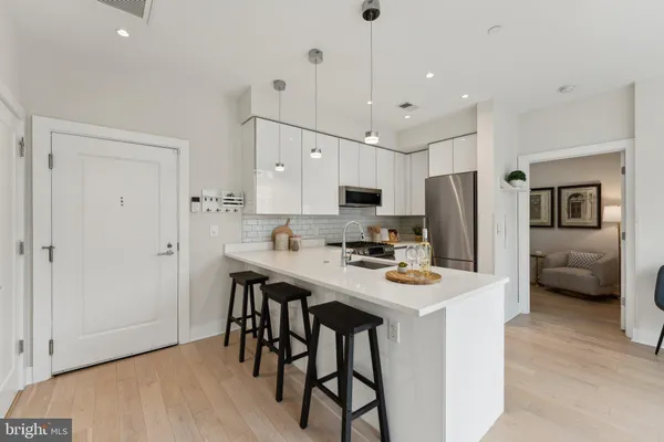 a kitchen with stainless steel appliances a refrigerator a stove a sink a dining table and chairs