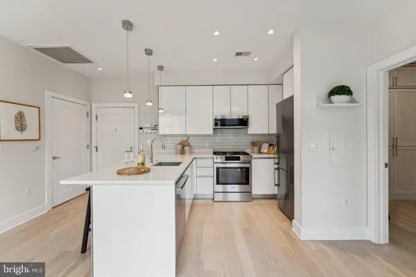 a kitchen with kitchen island a stove a sink a refrigerator and cabinets