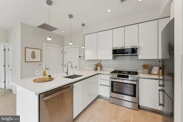 a kitchen with stainless steel appliances granite countertop a sink stove a refrigerator and white cabinets with wooden floor