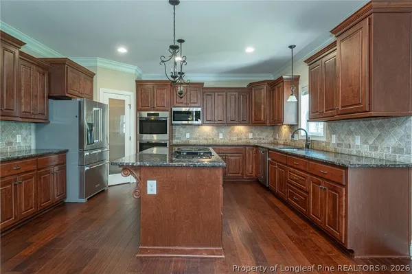a kitchen with stainless steel appliances granite countertop a refrigerator a sink dishwasher a stove and white countertops with wooden floor