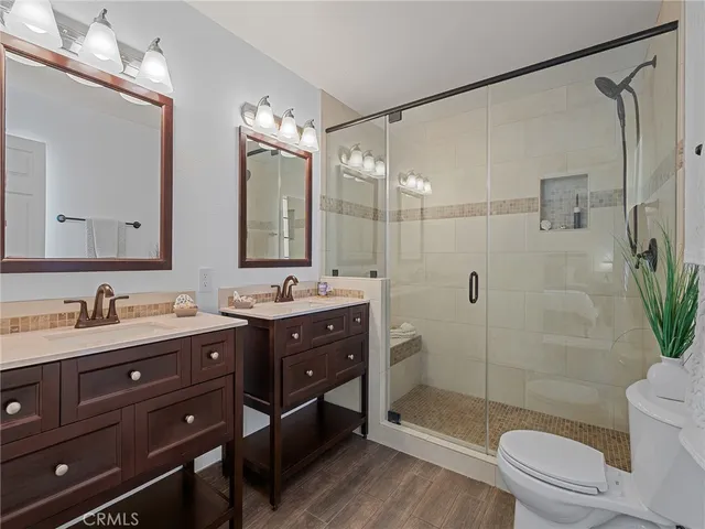 a bathroom with a double vanity sink toilet mirror and shower