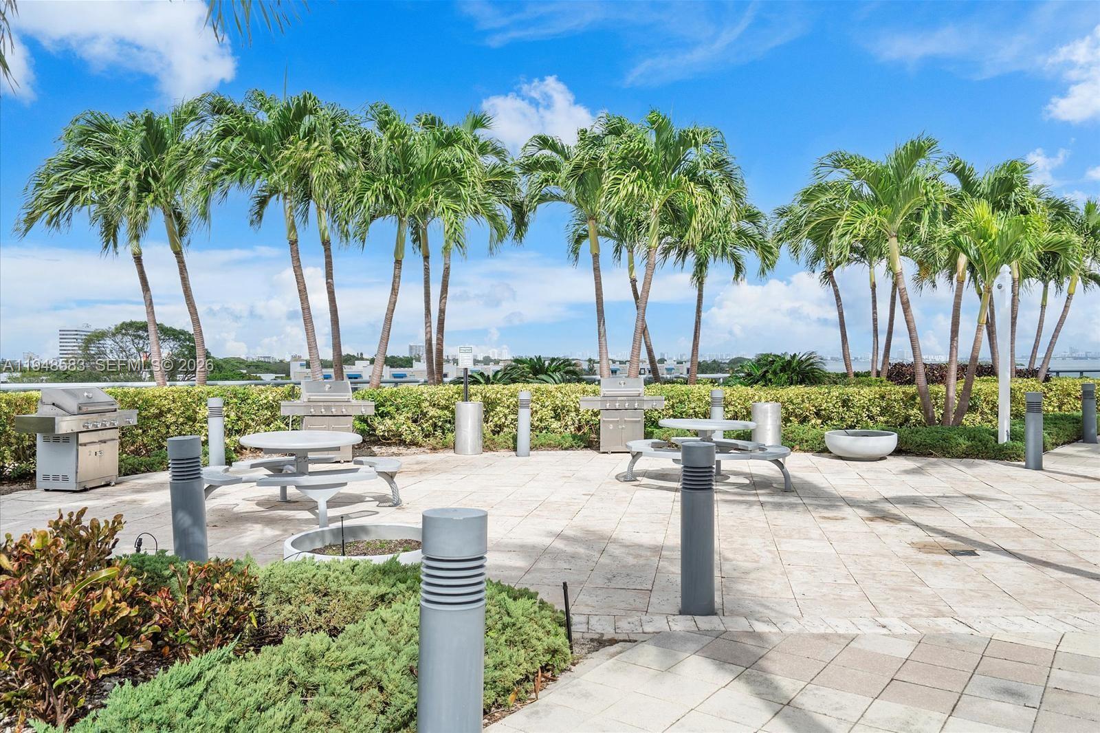601 Northeast 36th Street, Unit 1310 Miami, FL 33137 - Photo 17 of 40 a view of a patio with table and chairs under palm tree