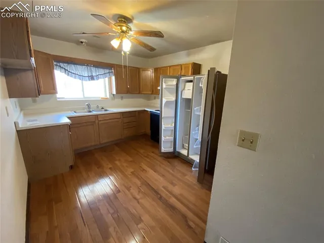 a kitchen with stainless steel appliances granite countertop a refrigerator a sink dishwasher a stove and white countertops with wooden floor