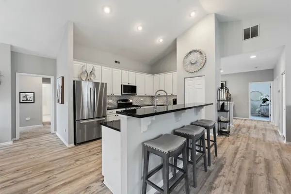 a kitchen with stainless steel appliances kitchen island granite countertop a stove top oven a sink dishwasher a dining table and chairs with wooden floor