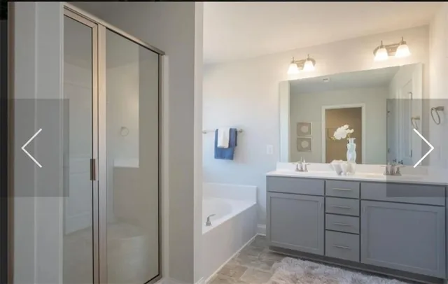 a en suite bathroom with a double vanity sink a mirror and a bathtub