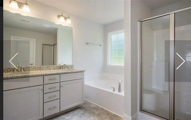 a bathroom with a granite countertop sink mirror and a bathtub