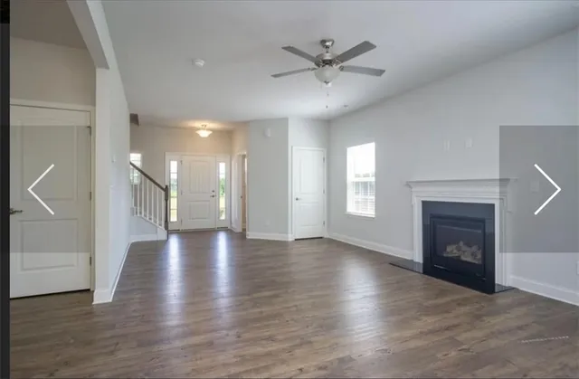 an empty room with wooden floor fireplace and windows