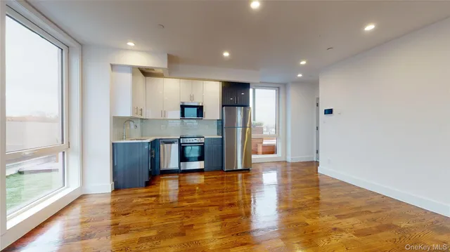 a view of kitchen with kitchen island granite countertop a refrigerator oven a sink and a counter top space
