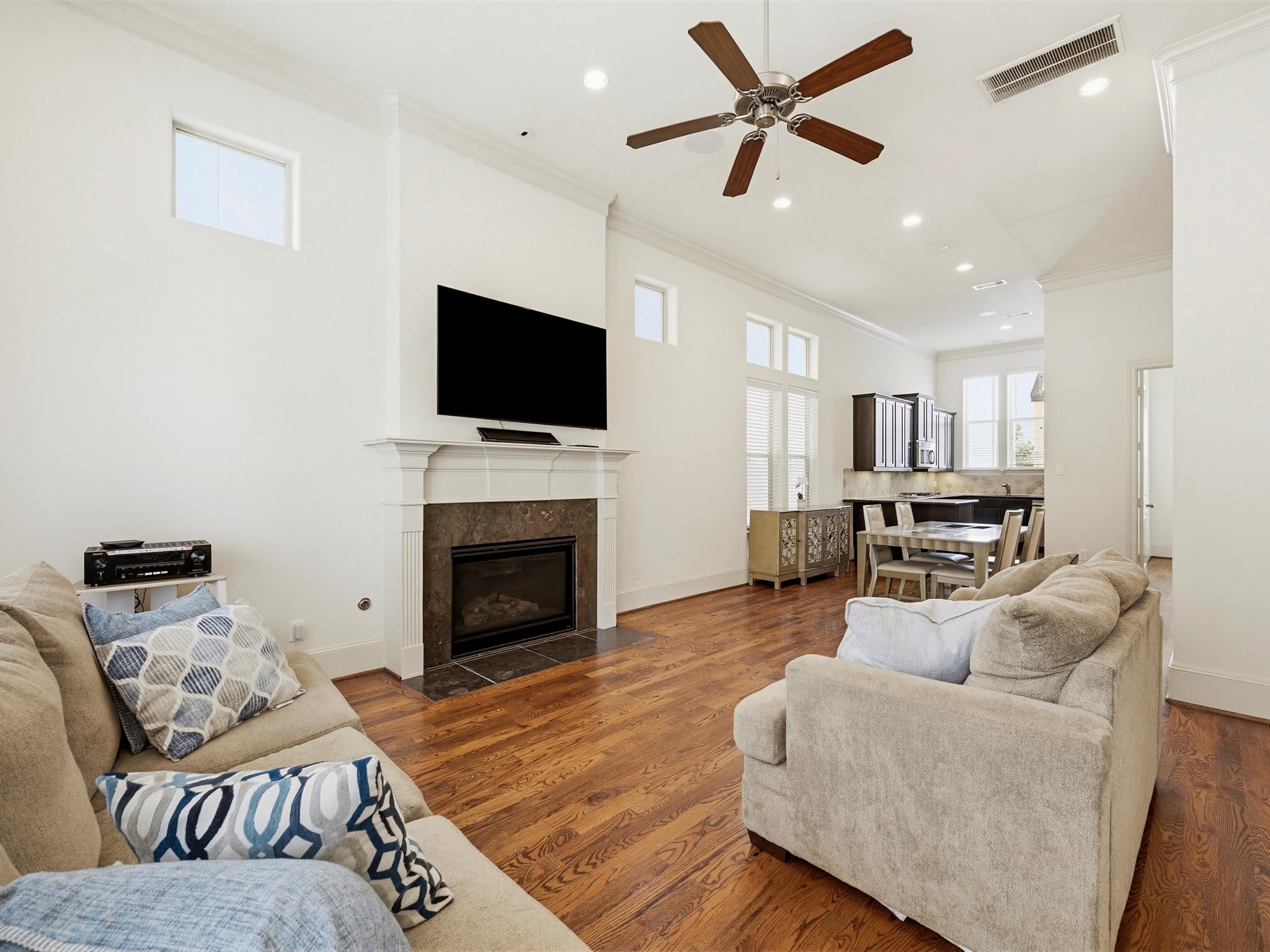 9427 London Bridge Station Houston, TX 77045 - Photo 13 of 30 Discover an inviting living area with an open layout featuring hardwood floors, a cozy fireplace, and a ceiling fan, seamlessly connecting to a modern kitchen with stainless steel appliances and a dining area—perfect for entertaining.