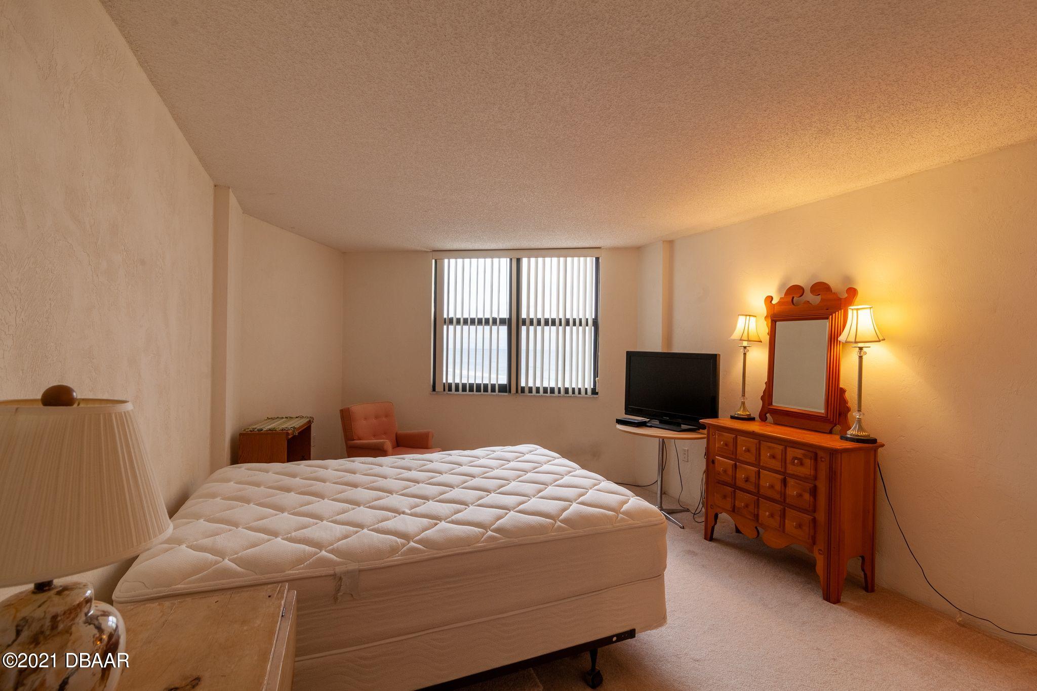 1415 Ocean Shore Boulevard, Unit 903 Ormond Beach, FL 32176 - Photo 17 of 47 a bedroom with a bed tv and a window